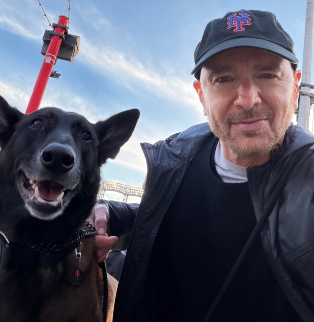 Atma in a Mets cap with Beast, a Belgian Malinois, outdoors in New York